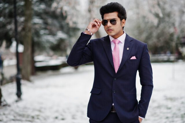 Elegant indian macho man model on suit and pink tie, sunglasses posed on winter day.